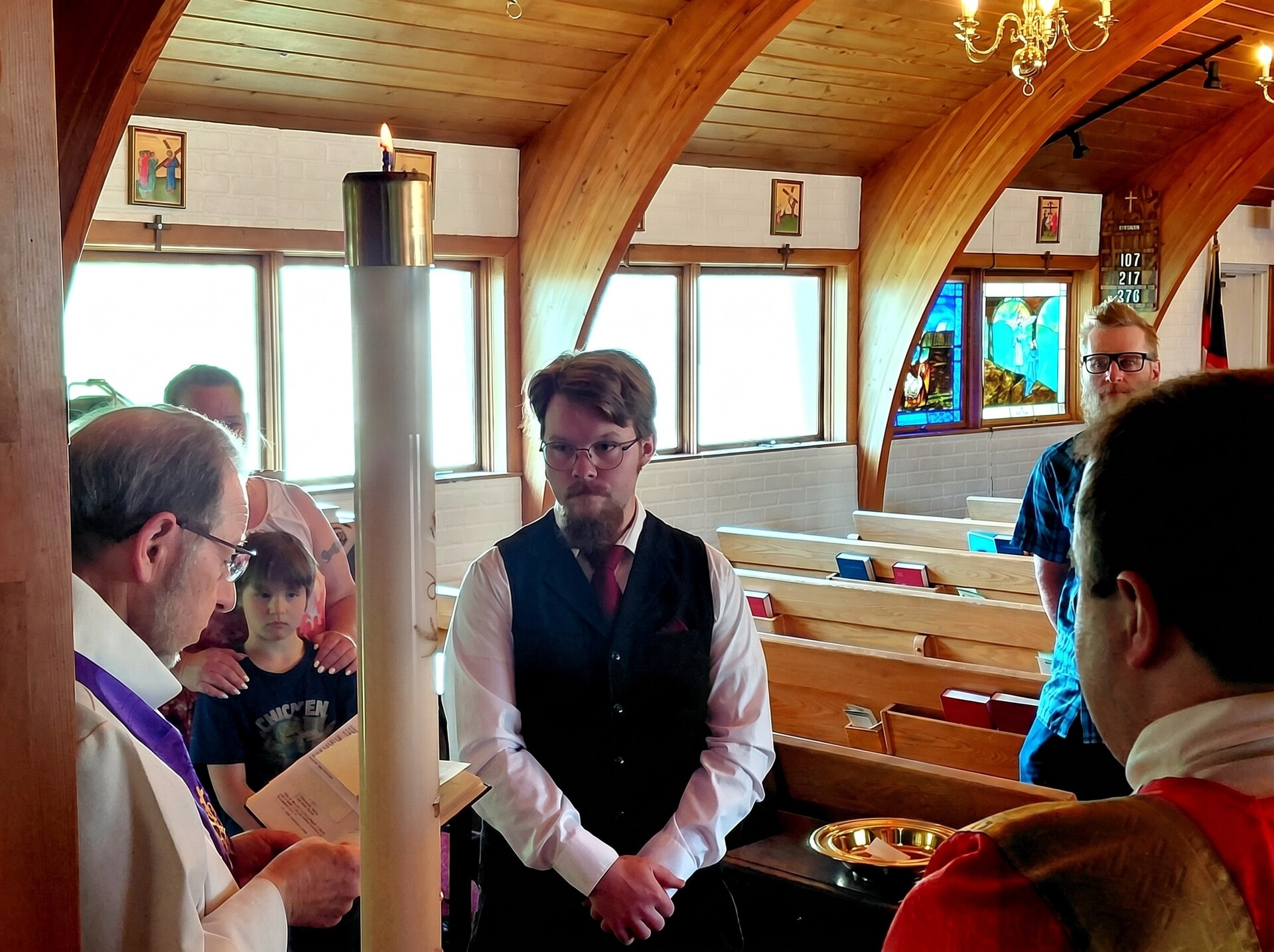The parish gathered around the font on Whitsunday, the Paschal candle burning beside the priest