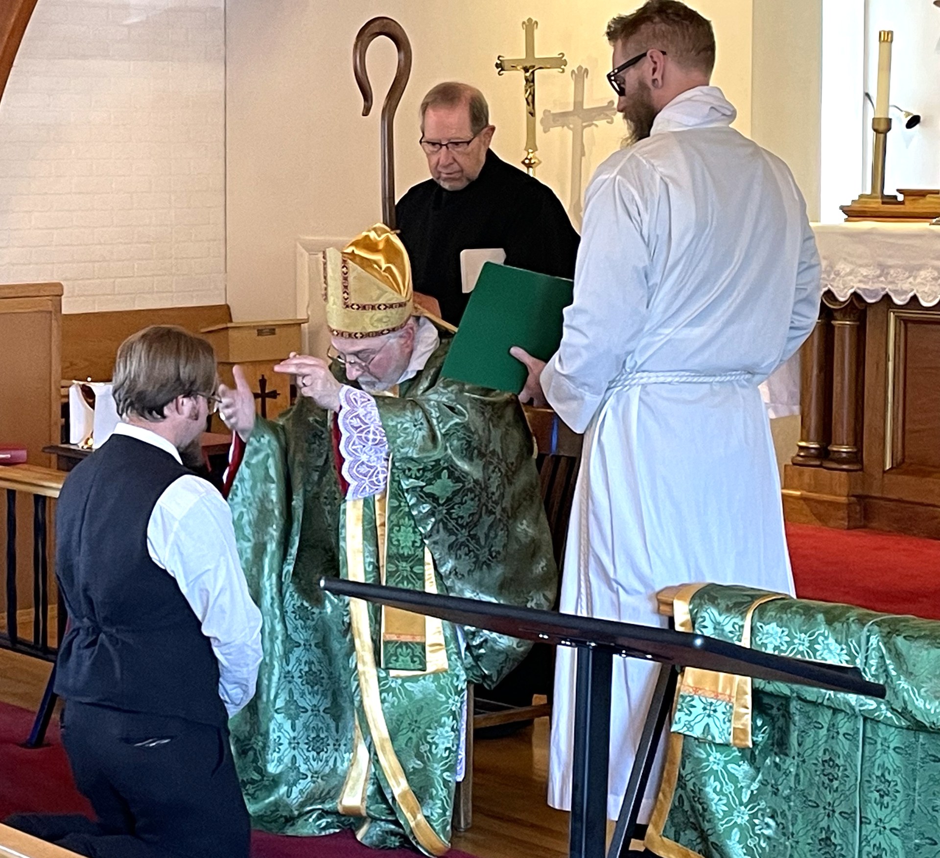 A candidate kneels before the bishop, who signs his forehead with the sign of the Cross